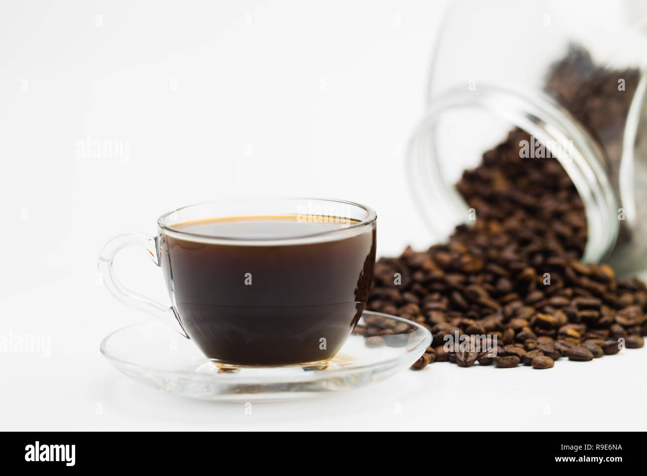 I chicchi di caffè e una tazza di caffè nero su uno sfondo bianco, studio luce Foto Stock