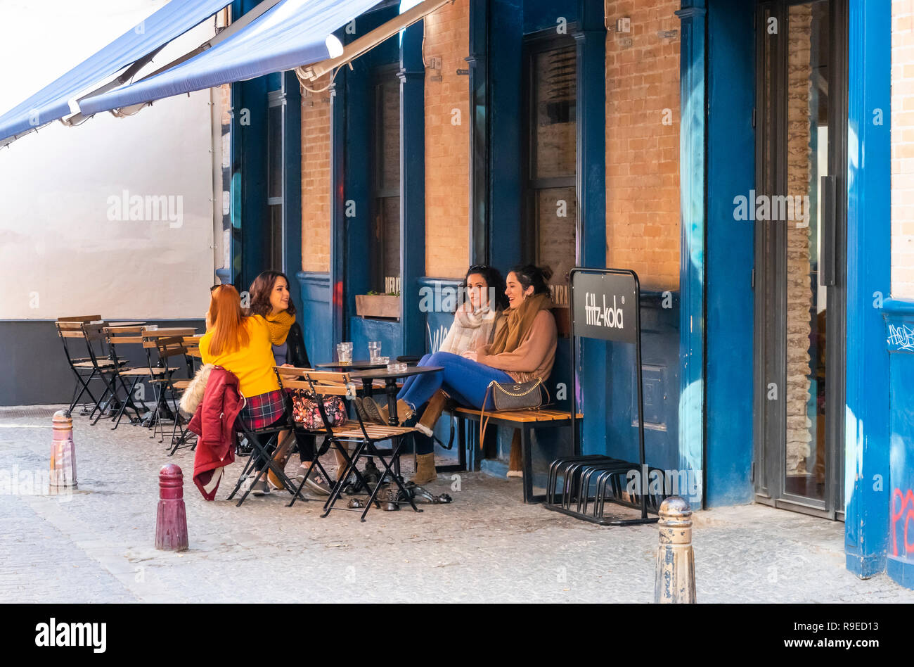 Quattro giovani donne sempre insieme per un drink e parlare a un alfresco al di fuori del tavolo in un bar a Siviglia, Spagna Foto Stock