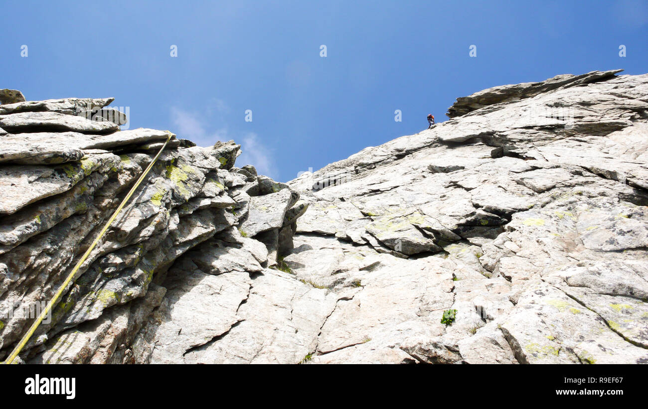 Rocciatore rappelling su un percorso di arrampicata nelle Alpi della Svizzera Foto Stock