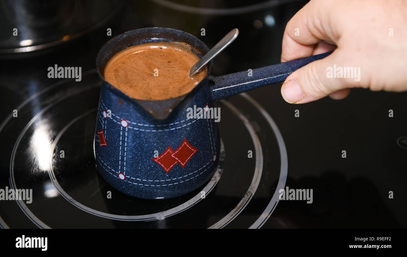 La produzione di birra caffè turco a casa, close-up, nessuno, maschio agitazione a mano il caffè con un cucchiaio Foto Stock