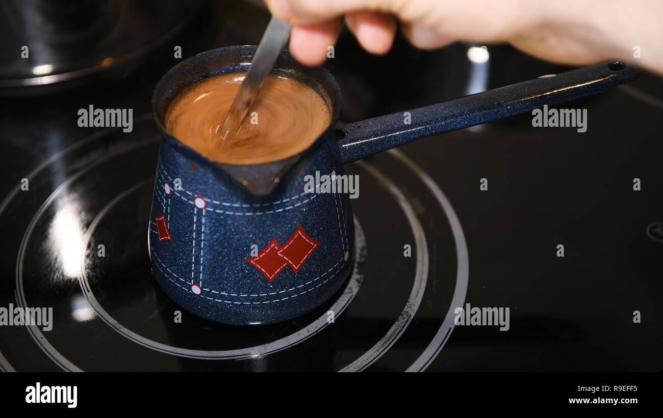 La produzione di birra caffè turco a casa, close-up, nessuno, maschio agitazione a mano il caffè con un cucchiaio Foto Stock