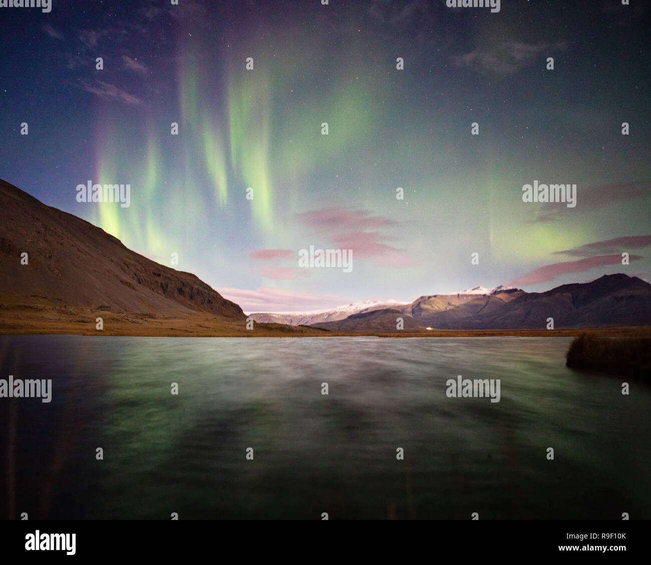 Aurora boreale luci del nord su un lago Islanda Nuvole rosa Foto Stock