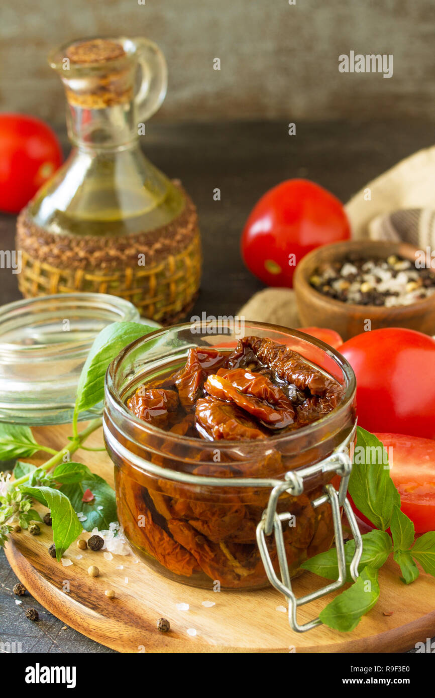 Pomodori secchi con olio di oliva in un recipiente su pietra nera o calcestruzzo tabella. Copia dello spazio. Foto Stock