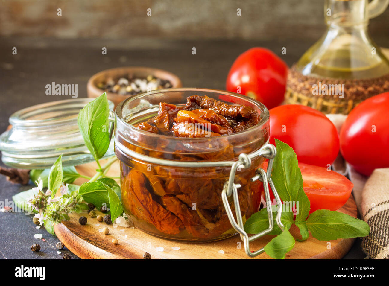 Pomodori secchi con olio di oliva in un recipiente su pietra nera o calcestruzzo tabella. Copia dello spazio. Foto Stock