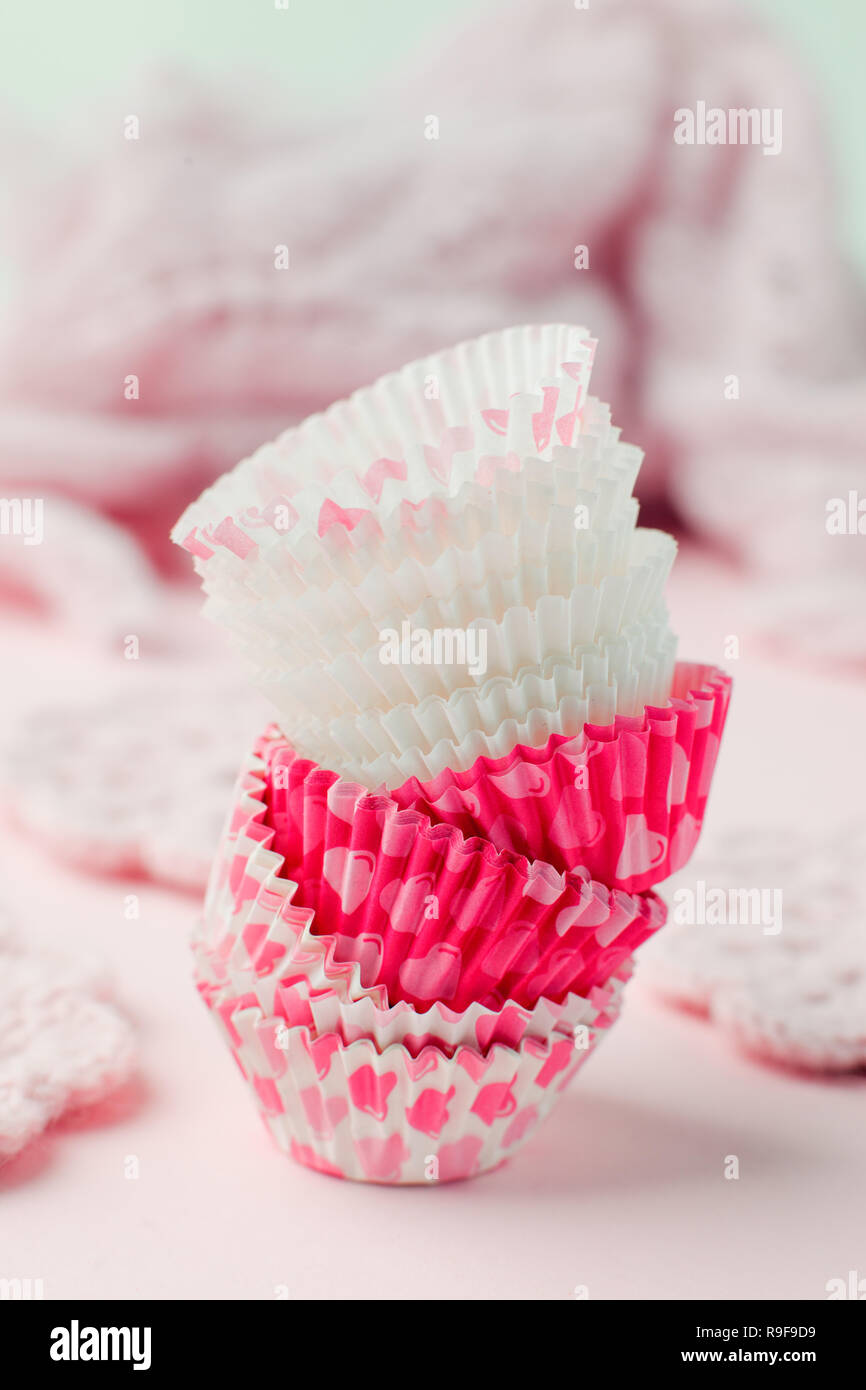 Tortina casi torre in una varietà di colori e dimensioni sulla tavola rosa pronto per la celebrazione di vacanza, il concetto di cottura. Carta caso di cottura per cupcake muffin e Foto Stock