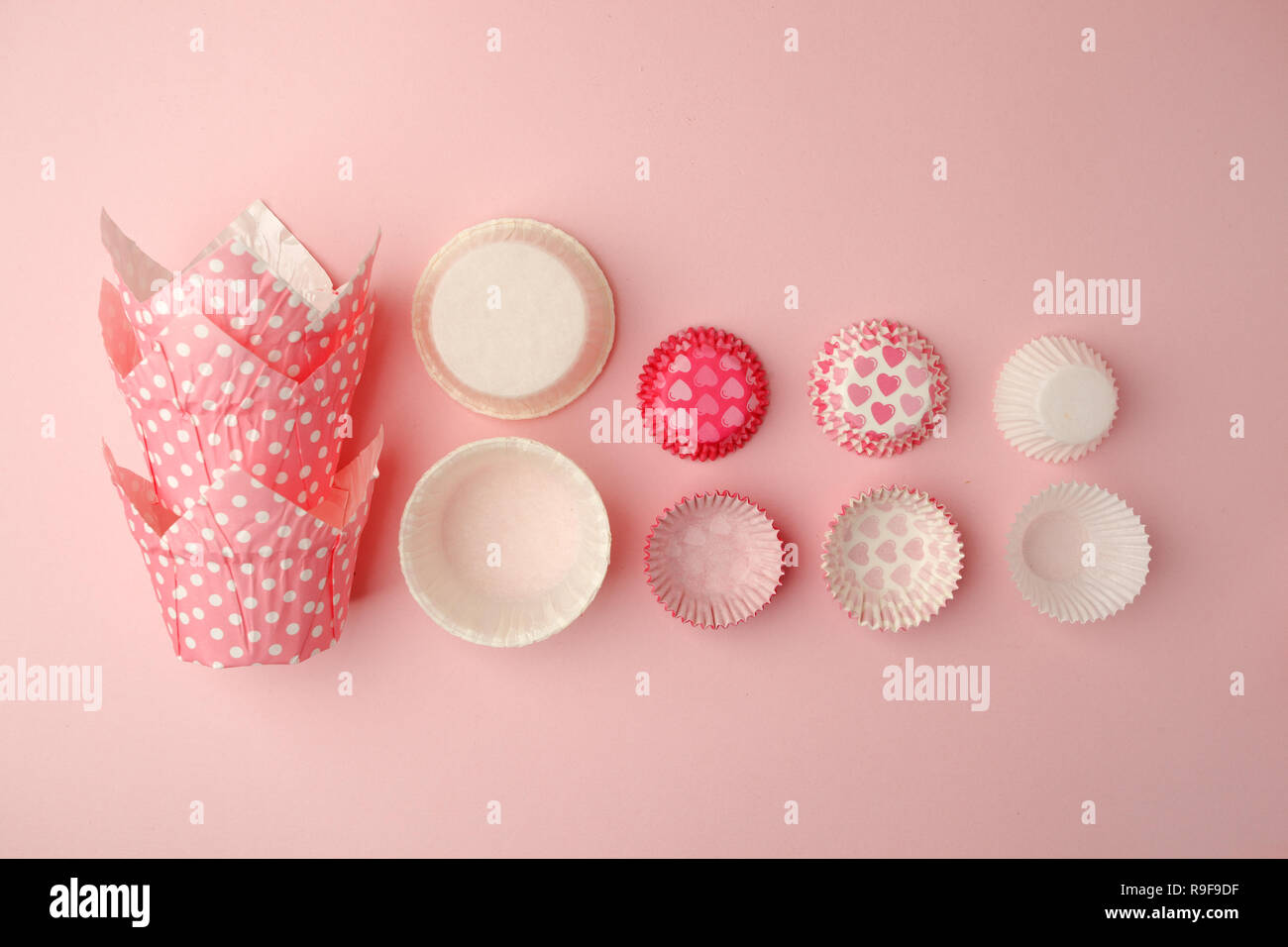 Tortina casi torre in una varietà di colori e dimensioni sulla tavola rosa pronto per la celebrazione di vacanza, il concetto di cottura. Carta caso di cottura per cupcake muffin e Foto Stock