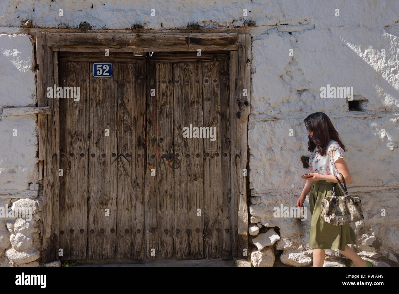 Donna passando per la porta di legno di una vecchia casa, Prizren, Kosovo Foto Stock