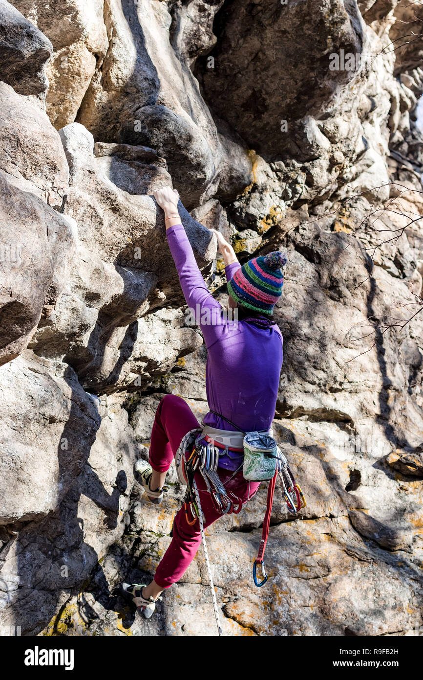 Ragazza rocciatore arrampicate su roccia in abiti colorati e un cappello in autunno Foto Stock