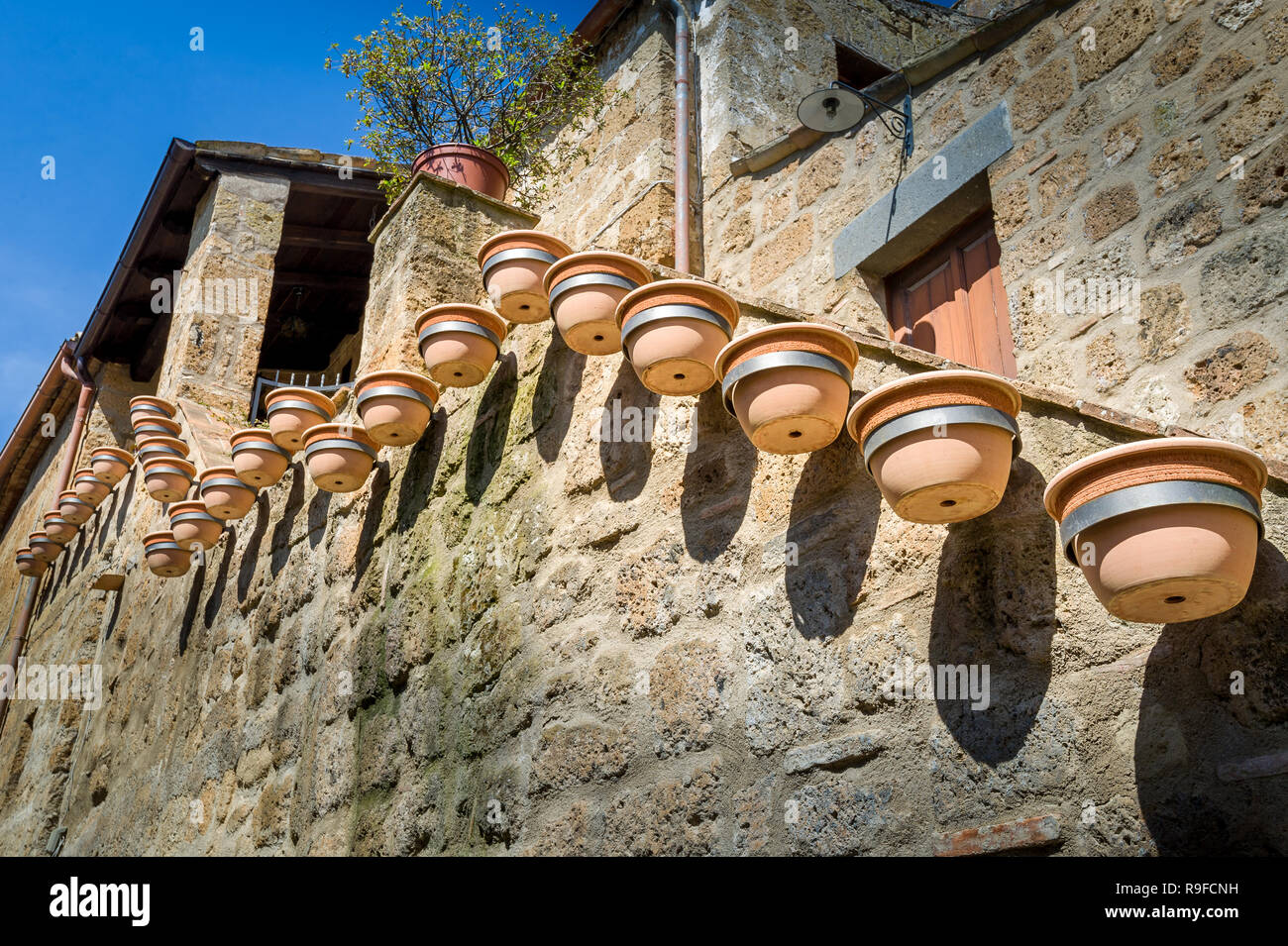 Muro medievale decorato con molti vasi di fiori. Civita di Bagnoregio, Toscana, Italia. Foto Stock