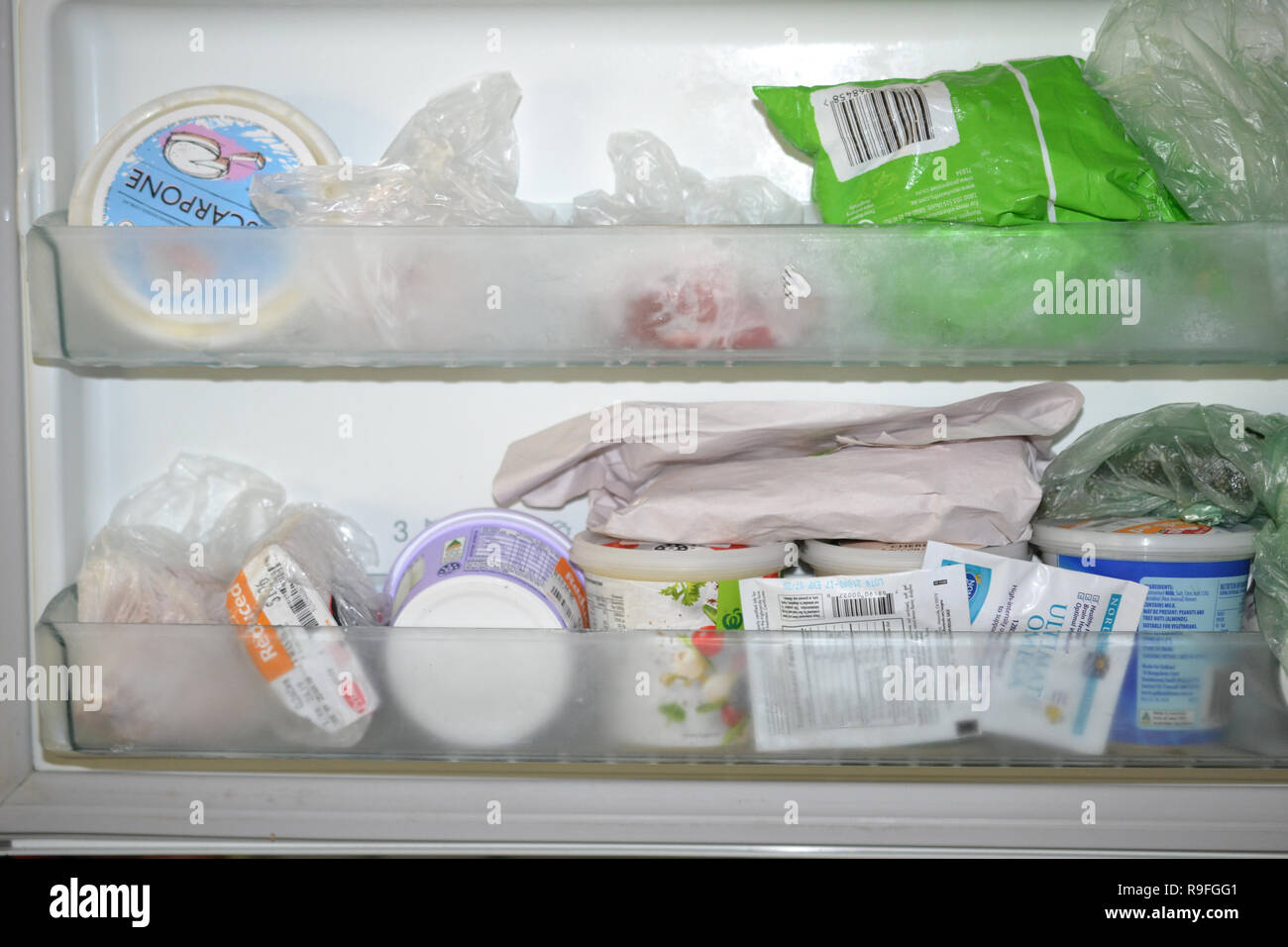 Lo sportello del freezer scomparti riempiti con i contenitori per alimenti e cibi confezionati Foto Stock