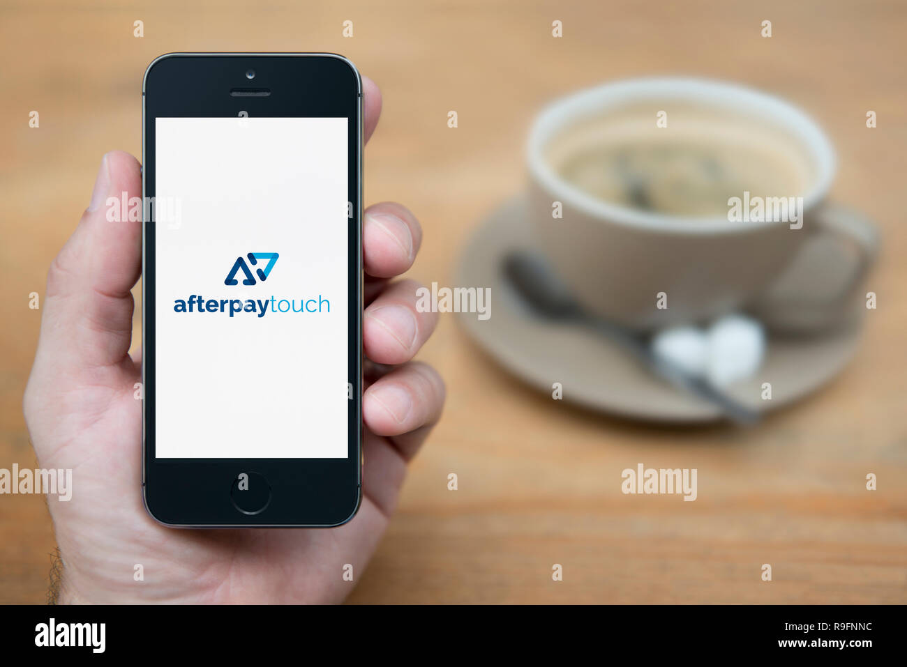 Un uomo guarda al suo iPhone che visualizza il Afterpay Touch logo (solo uso editoriale). Foto Stock