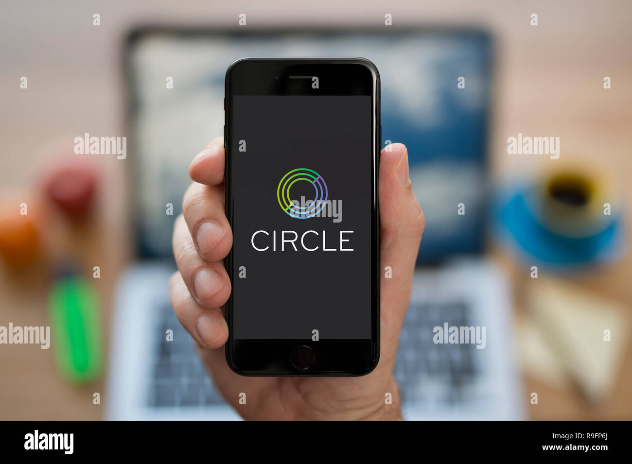 Un uomo guarda al suo iPhone che visualizza il logo del cerchio (solo uso editoriale). Foto Stock