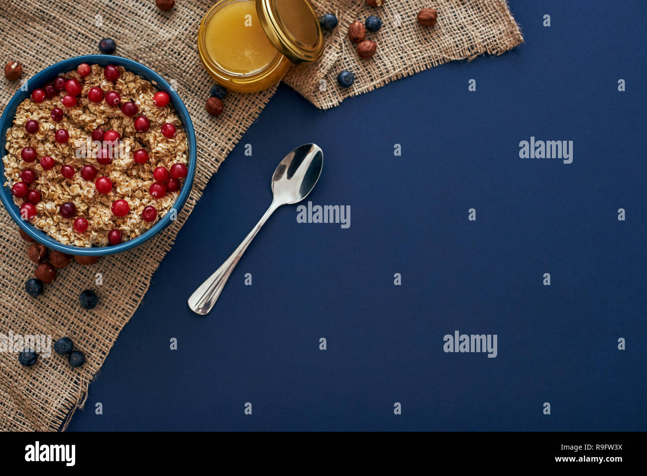 Dolce e sana prima colazione. Foto ritagliata della farina di avena con frutti di bosco, noci e miele. Mirtilli rossi e mirtilli. Foto Stock