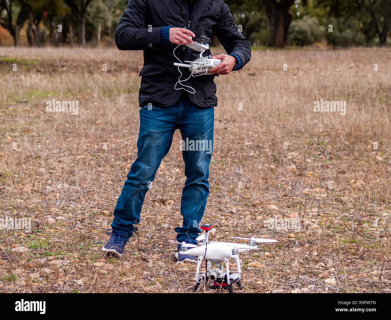 Un drone pilota configurando il suo drone nella foresta prima di volare Foto Stock