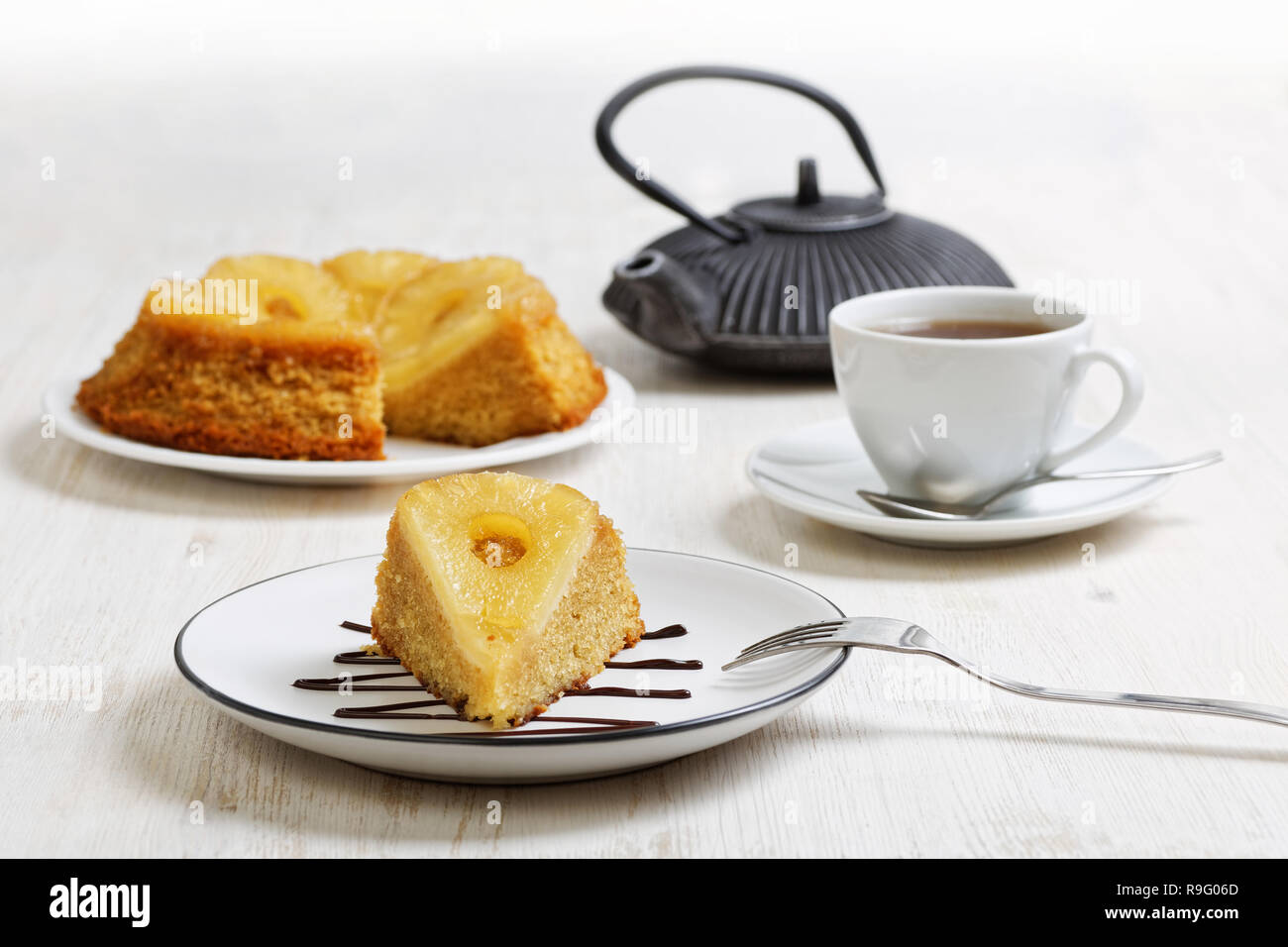Pezzo di ananas torta rovesciata, teiera e tazza di tè bianco su un tavolo di legno. Messa a fuoco poco profonde. Foto Stock