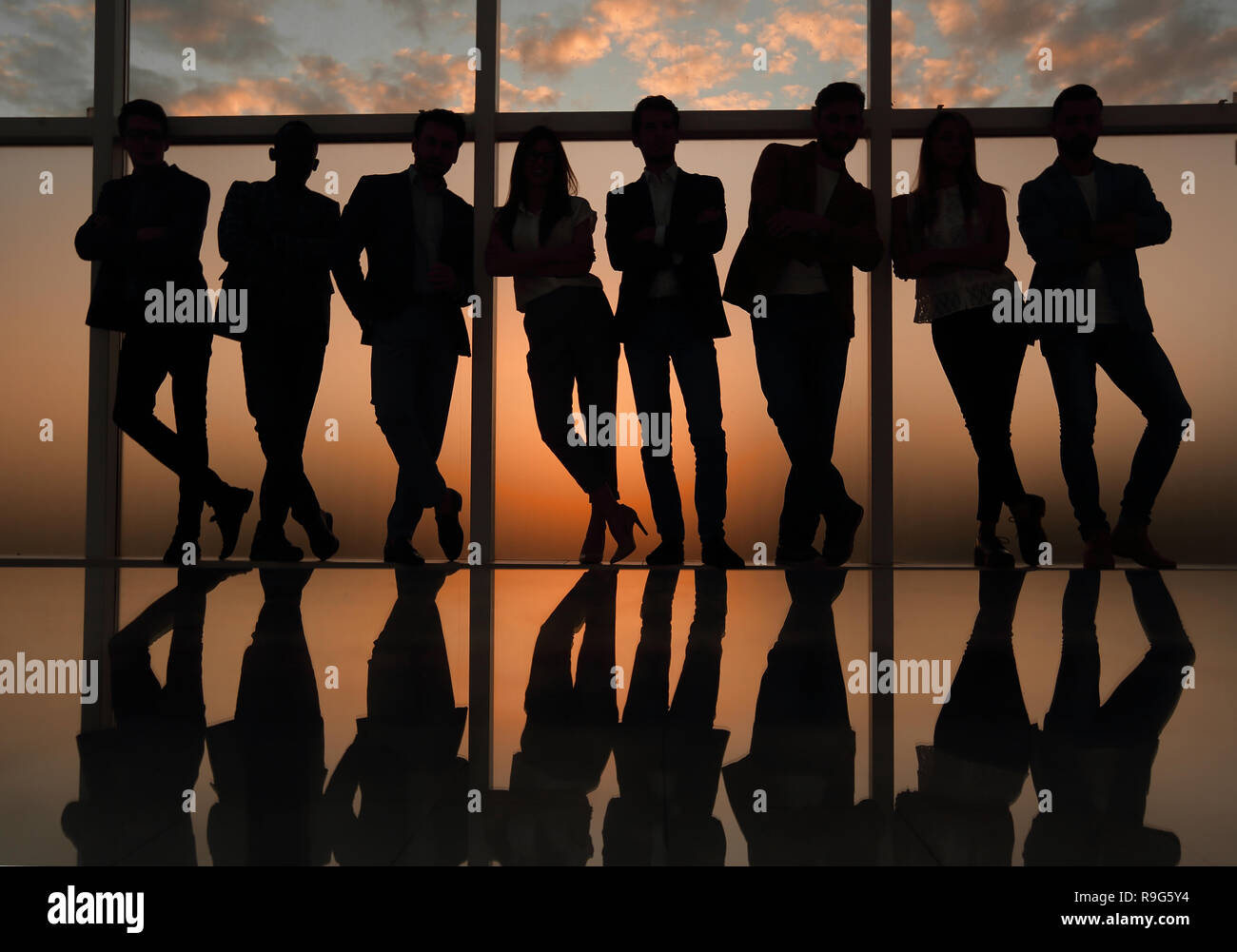 Silhouette di un team aziendale in piedi accanto alla finestra di ufficio Foto Stock
