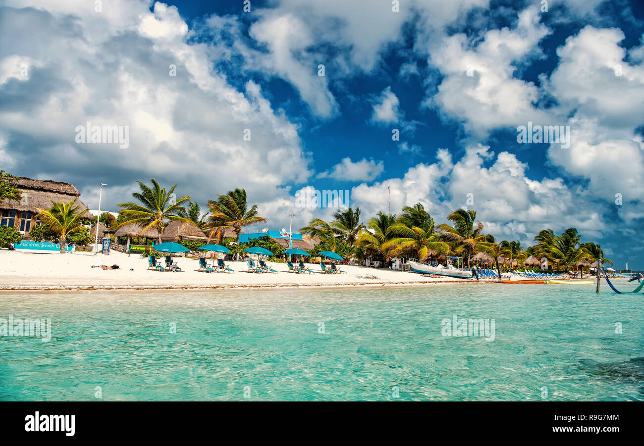 Costa Maya, Messico - 01 Febbraio 2016: Spiaggia verde con alberi di palma, ombrelloni sulla sabbia. Mare o acqua oceanica a Costa Maya, Messico. Resort tropicale sulla giornata di sole su nuvoloso cielo blu. Le vacanze estive, il concetto di viaggio. Foto Stock