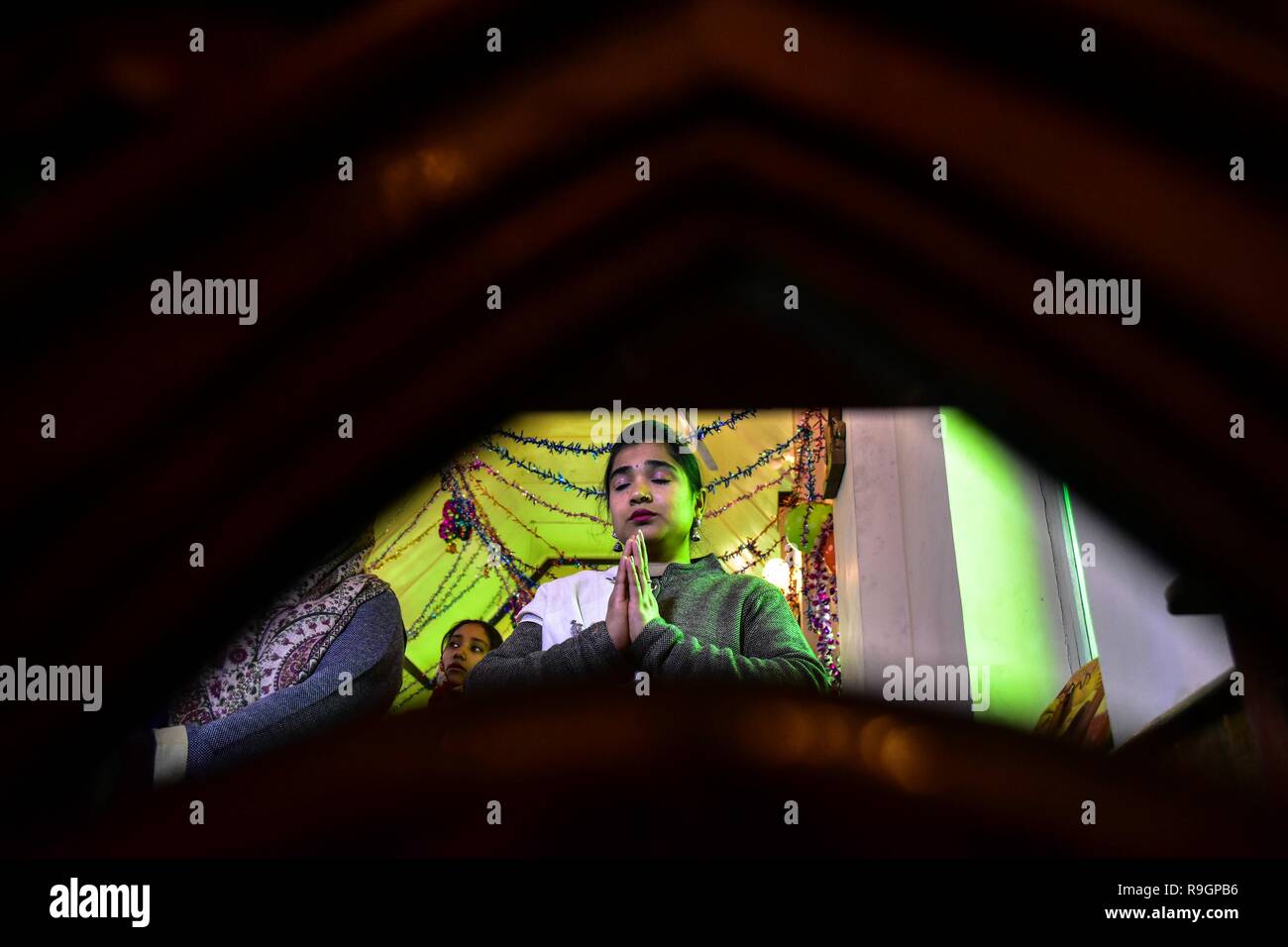 Srinagar, India. 25 Dic, 2018. Un cristiano del Kashmir prega all'interno della Santa Famiglia Chiesa cattolica in occasione del Natale a Srinagar, Indiano Kashmir amministrato. In mezzo a un freddo pungente in onda lo stato, la comunità cristiana della valle di martedì ha celebrato il Natale; il giorno della nascita di Gesù Cristo, con la scorza e allegria a Srinagar. Tra quelli che hanno pregato erano i turisti provenienti da diverse parti del paese che hanno aderito alla gente del posto per il giorno fausto e pregato per la pace in Kashmir e del resto del mondo. Credito: SOPA Immagini limitata/Alamy Live News Foto Stock