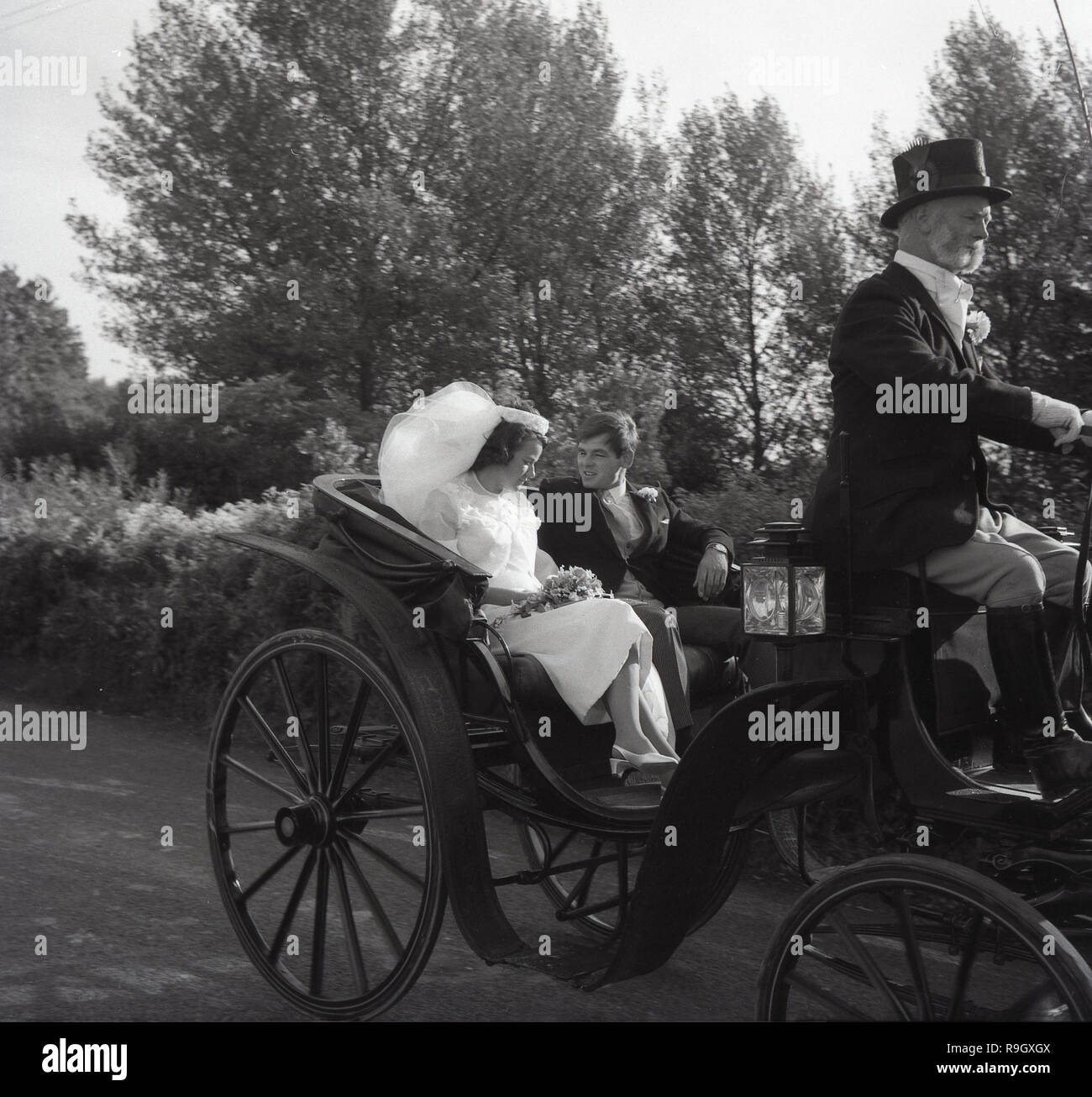 1967, storico, la sposa e lo sposo seduto nella parte posteriore di un antico open-top cavallo pilotato carrello essendo azionato per la ricezione da parte del conducente in calzoncini e indossando un cappello a cilindro, Inghilterra, Regno Unito. Foto Stock