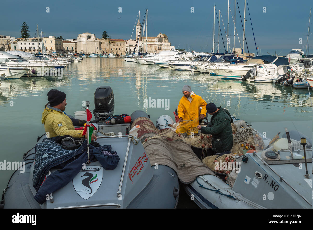 Pescatori al lavoro nel porto di Trani sul mare Adriatico con vista sul Duomo di San Nicola Pellegrino. , Puglia, Italia, Europa Foto Stock