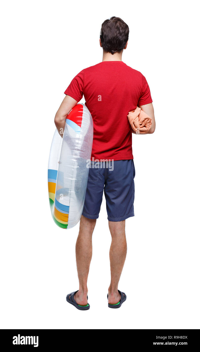 Vista posteriore di un uomo in pantaloncini corti con un cerchio gonfiabile. Il ragazzo sulla spiaggia. Vista posteriore di raccolta persone. vista posteriore di persona. Isolate su wh Foto Stock