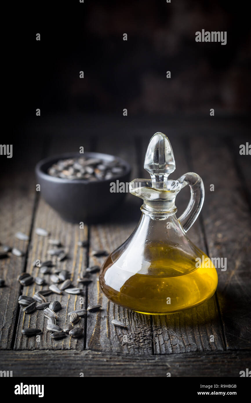 Organici di olio di semi di girasole in un piccolo vaso di vetro con olio di semi di girasole in legno scuro dello sfondo Foto Stock