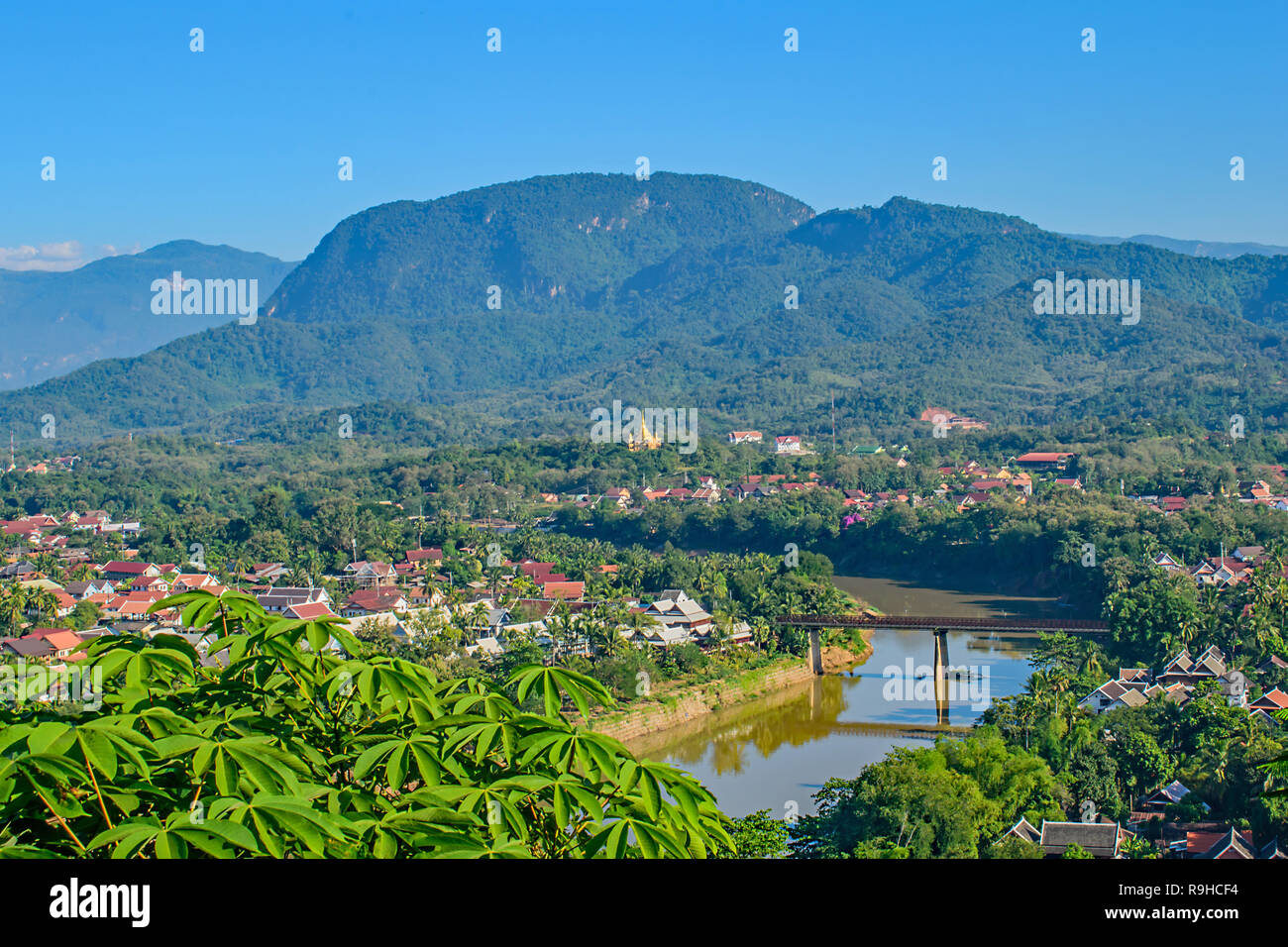 Una alta vista da Phou Si Hill Laos attraverso il ponte per i tetti colorati e colline oltre Foto Stock