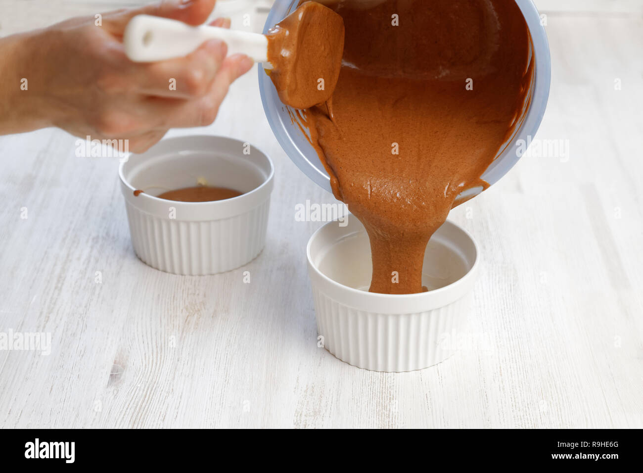 Impasto crudo viene versata in uno stampo in ceramica per la cottura di cioccolato dessert di mandorla Foto Stock