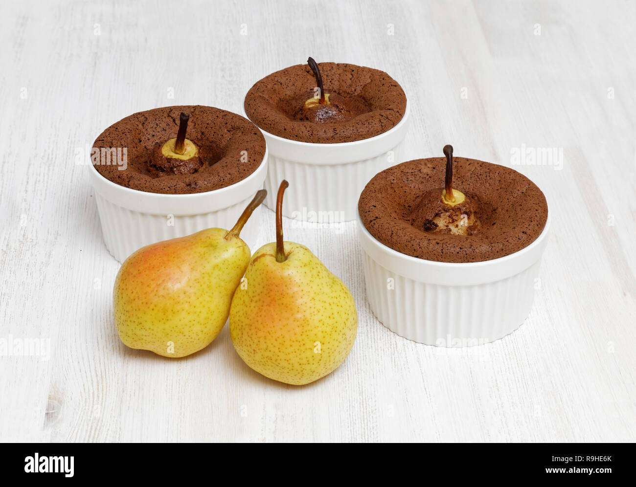 Il cioccolato-mandorla dolce con le pere in ceramica bianca teglia e due materie pera matura frutta bianca sul tavolo di legno Foto Stock