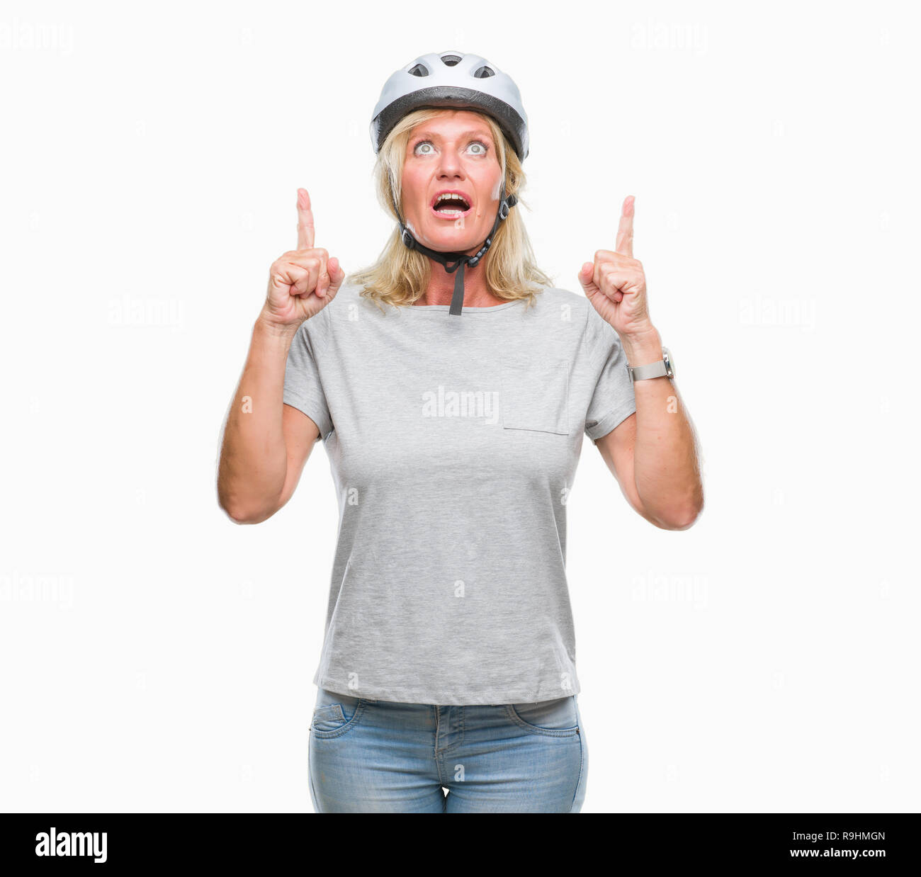 La mezza età caucasian ciclista donna che indossa il casco di sicurezza su sfondo isolato meravigliato e sorpreso cercando e dispositivo di puntamento con le dita e sollevato Foto Stock