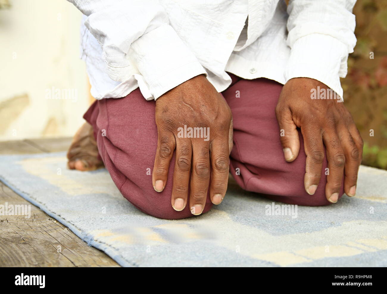 Uomo musulmano che prega con tappetino sul pavimento con foto di scorta Foto Stock