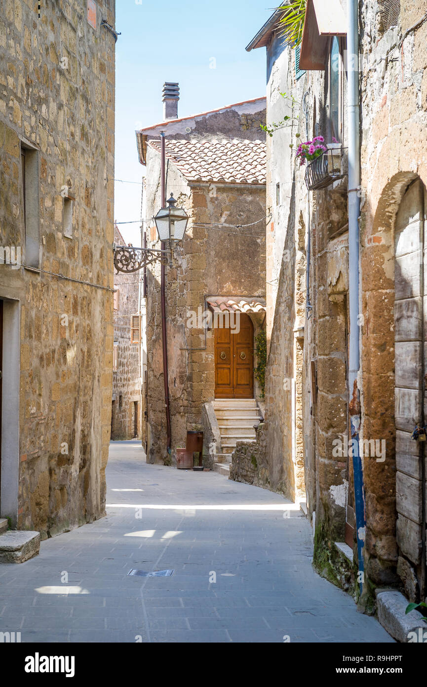 Pitigliano piccola strada con case antiche foto verticale. Toscana, Italia. Foto Stock