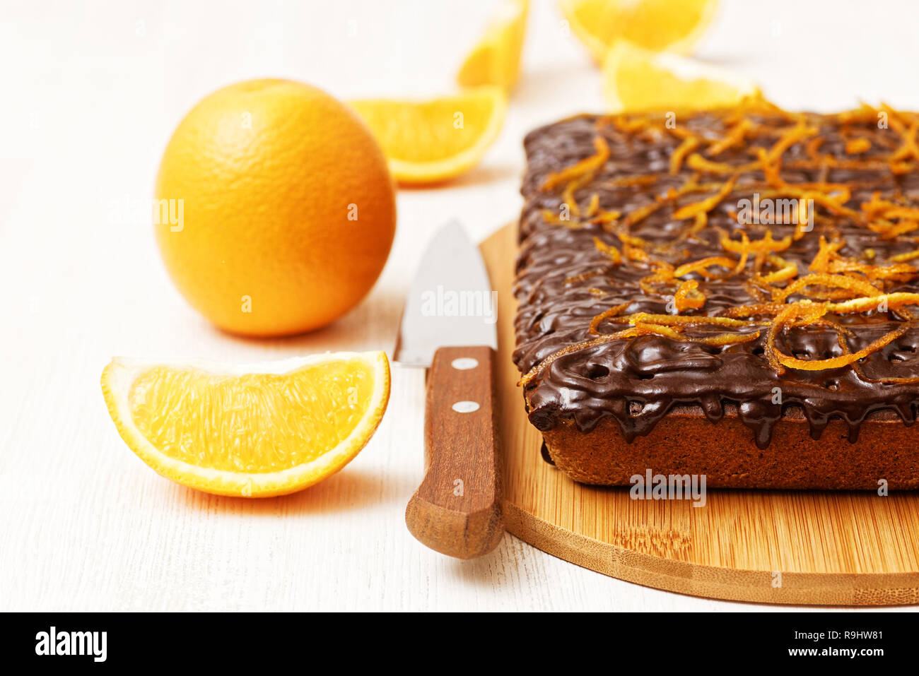 Cioccolata e arancio dolce con buccia di arancia vicino a Orange e il coltello sul bianco sullo sfondo di legno. Messa a fuoco poco profonde. Foto Stock