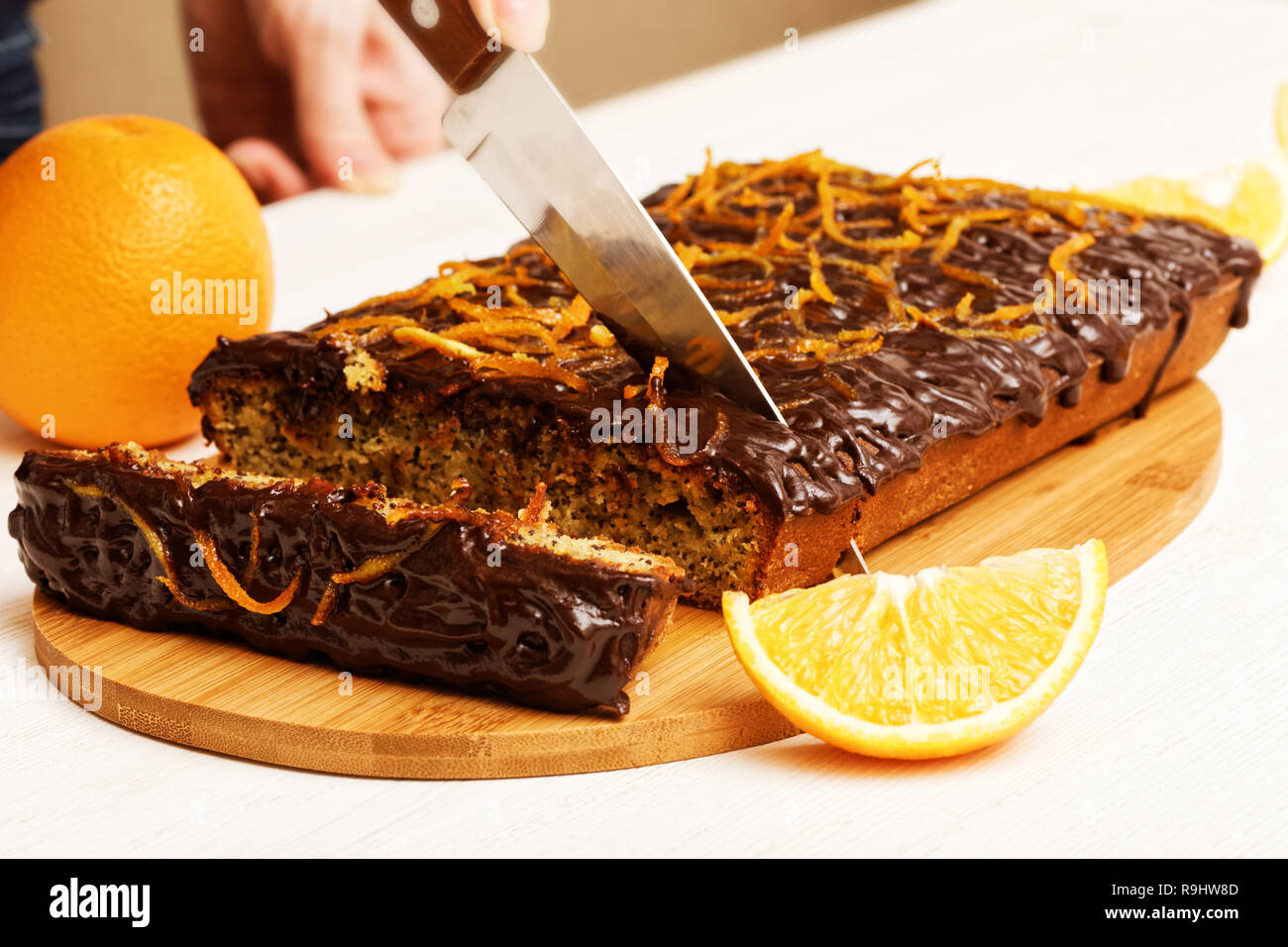 Casalinga tagliare il pezzo di cioccolato e torta arancione Foto Stock