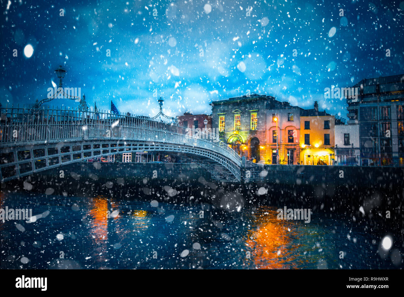 Vista serale di Dublino in Irlanda al Ha'penny Bridge del fiume Liffey con i fiocchi di neve caduta durante l'inverno tempesta di neve Foto Stock