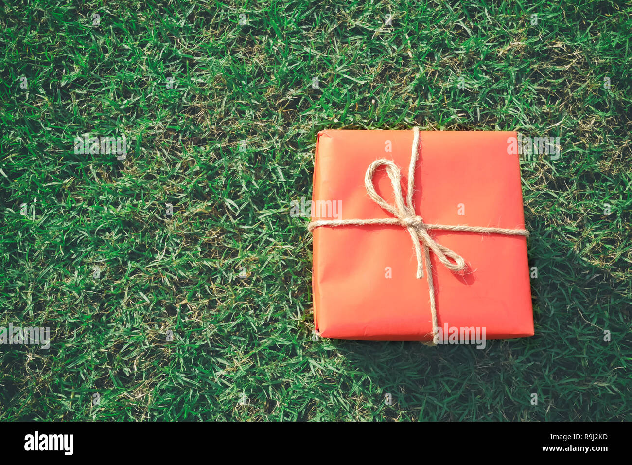 Confezione regalo rossa sul prato verde per il Natale e il nuovo anno, il giorno di san valentino o anniversario di giorno e di avere uno spazio di copia per il design nel suo concetto di lavoro. Foto Stock