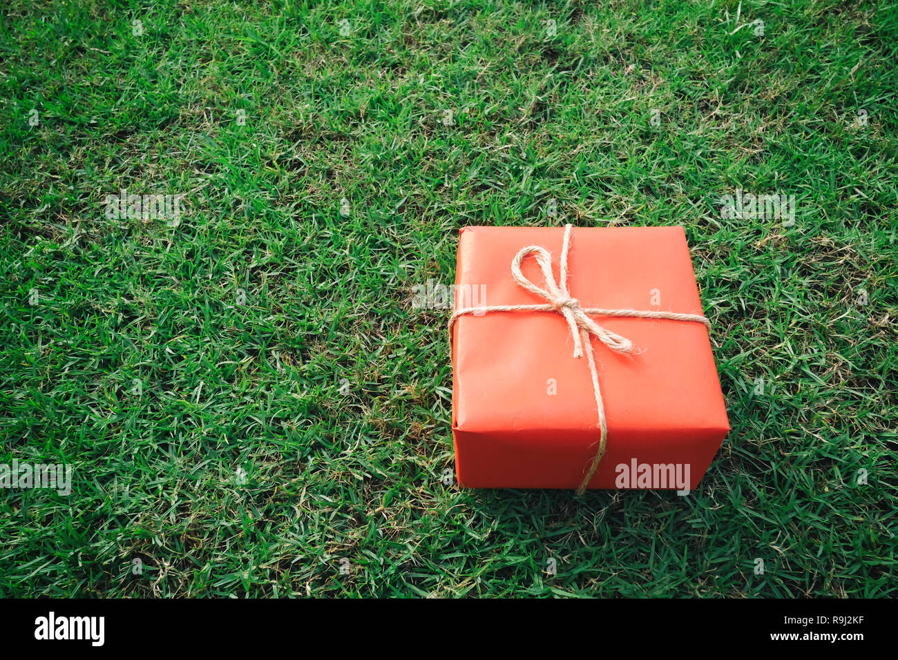 Confezione regalo rossa sul prato verde per il Natale e il nuovo anno, il giorno di san valentino o anniversario di giorno e di avere uno spazio di copia per il design nel suo concetto di lavoro. Foto Stock