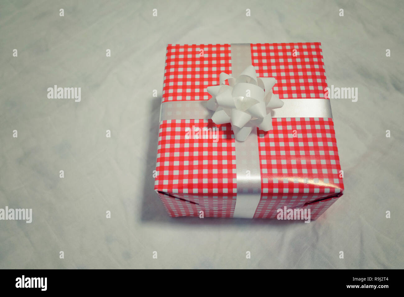 Confezione regalo rossa sul tessuto grigio per Natale e Capodanno, il giorno di san valentino o anniversario di giorno e di avere uno spazio di copia per il design nel suo concetto di lavoro. Foto Stock