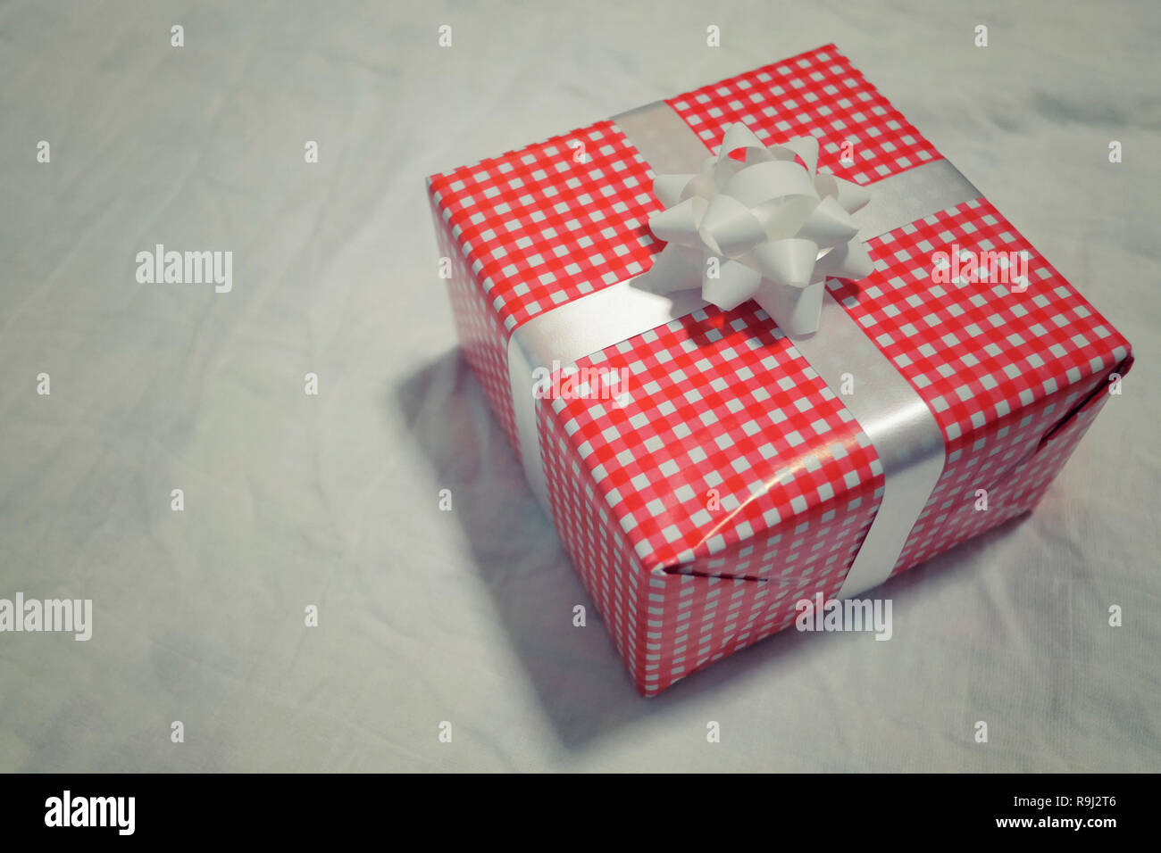 Confezione regalo rossa sul tessuto grigio per Natale e Capodanno, il giorno di san valentino o anniversario di giorno e di avere uno spazio di copia per il design nel suo concetto di lavoro. Foto Stock