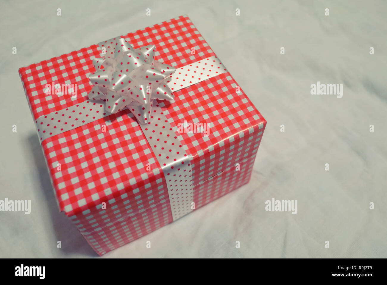 Confezione regalo rossa sul tessuto grigio per Natale e Capodanno, il giorno di san valentino o anniversario di giorno e di avere uno spazio di copia per il design nel suo concetto di lavoro. Foto Stock