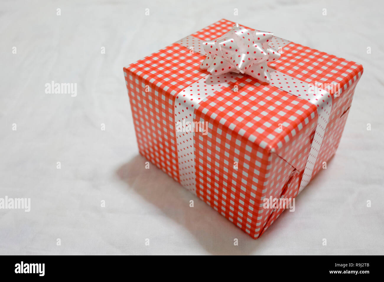 Confezione regalo rossa sul tessuto grigio per Natale e Capodanno, il giorno di san valentino o anniversario di giorno e di avere uno spazio di copia per il design nel suo concetto di lavoro. Foto Stock