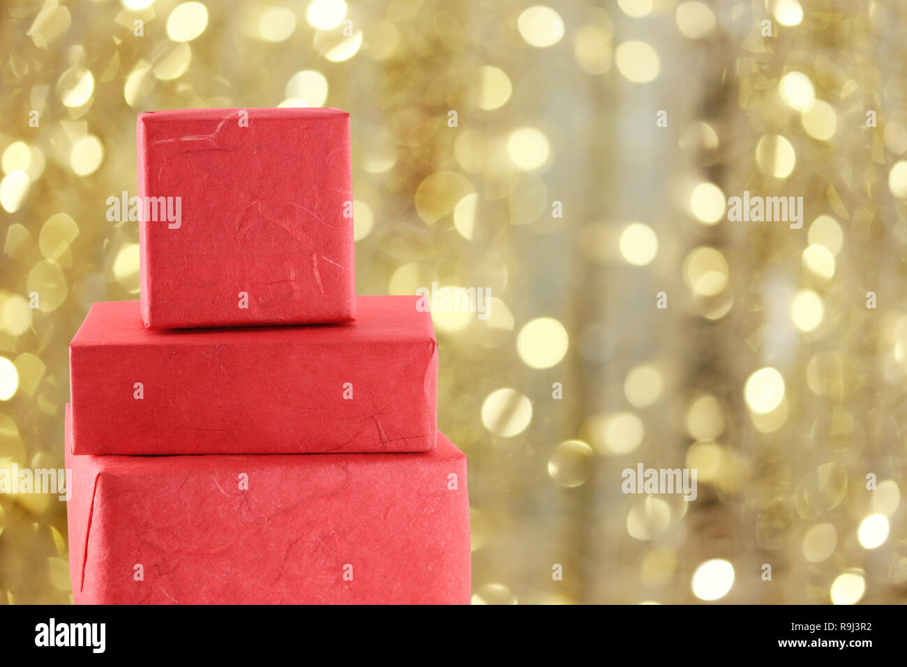 Confezione regalo rossa oro su sfondo bokeh di luci di Natale per la progettazione sullo sfondo nel vostro concetto di Natale. Foto Stock