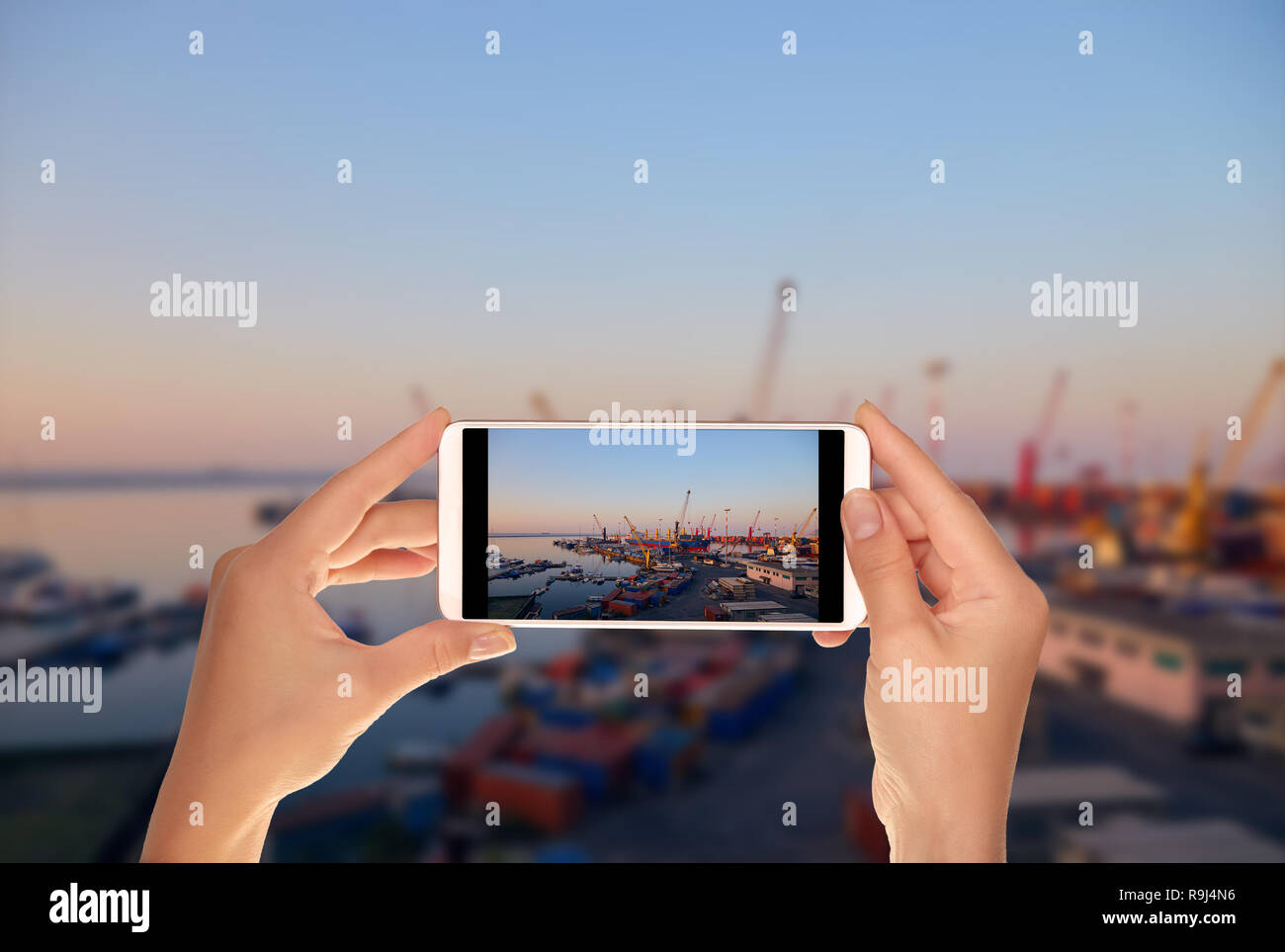 Un turista è scattare una foto del terminale della porta con la gru, navi e contenitori vicino Salerno all alba di un telefono cellulare Foto Stock