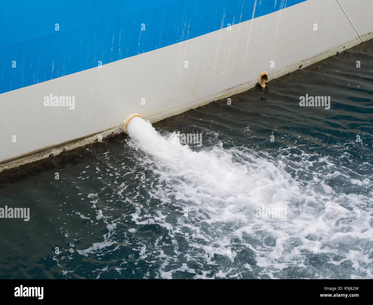 Acqua di sentina pompata fuori del lato di una nave in acqua del porto Foto Stock