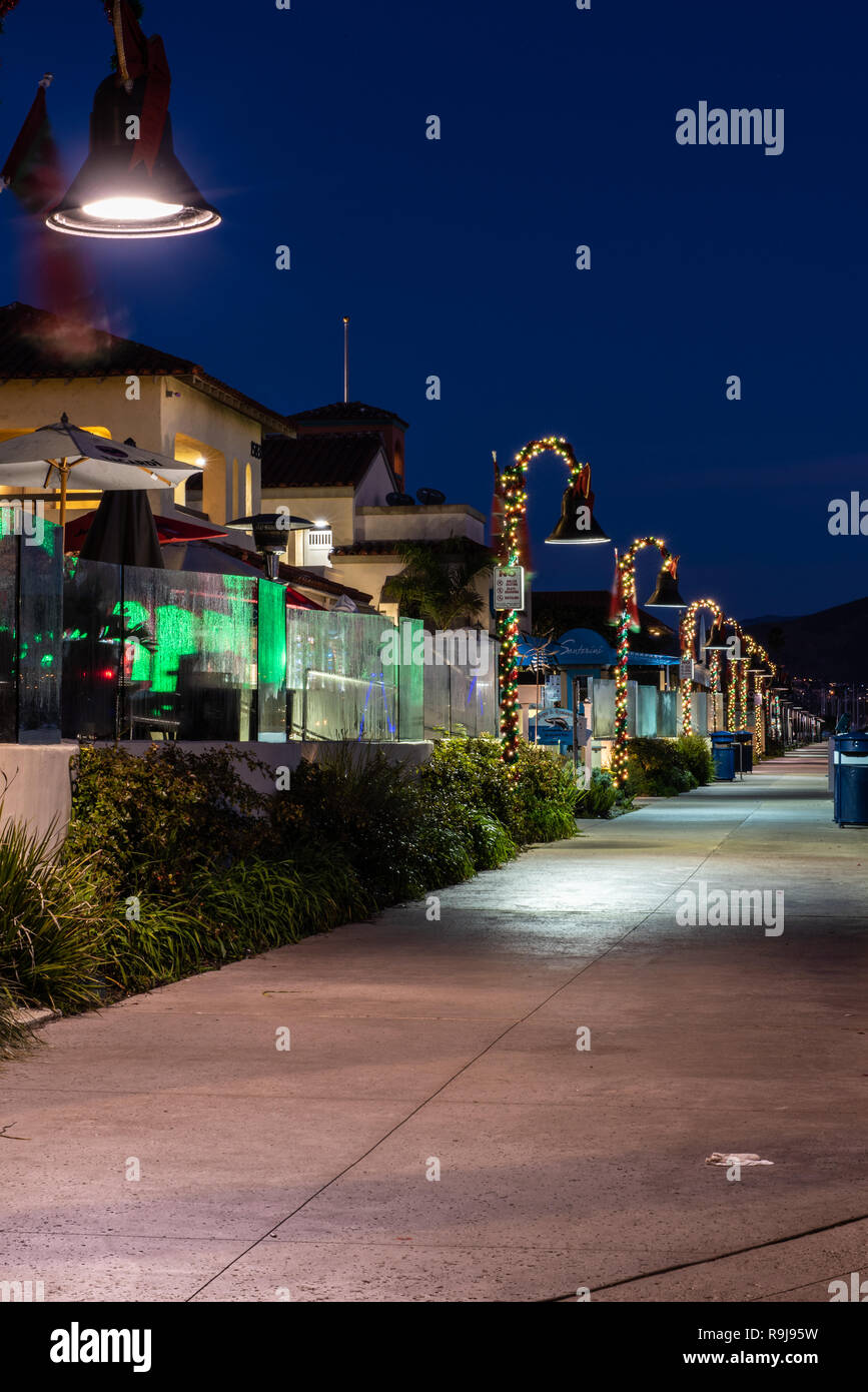 Le luci di Natale avvolti intorno alle lampade al di sotto predawn sky lungo Ventura Harbor negozi in California, Stati Uniti d'America il 24 dicembre 2018. Foto Stock