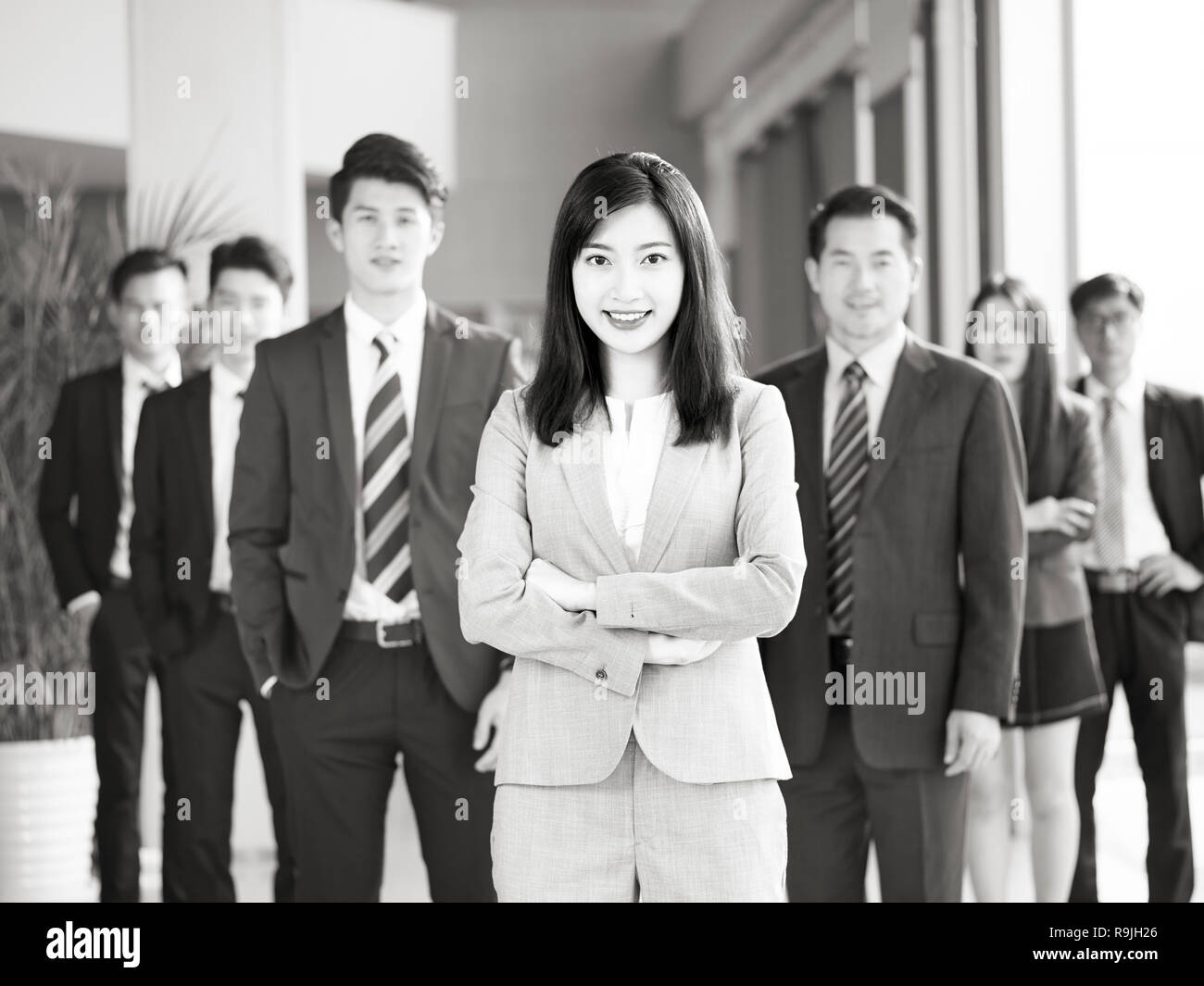 Ritratto di un team di successo di imprenditori asiatici e imprenditrici, guardando la telecamera sorridendo, in bianco e nero. Foto Stock