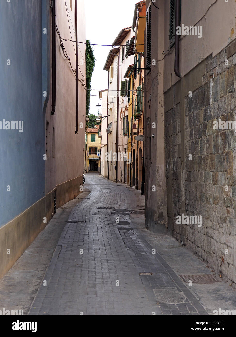 Avvolgimento tipico toscano strette strade lastricate in ombra con la pianura parete blu e muratura in pietra, pluviali e finestre con persiane in Pisa, Italia Foto Stock