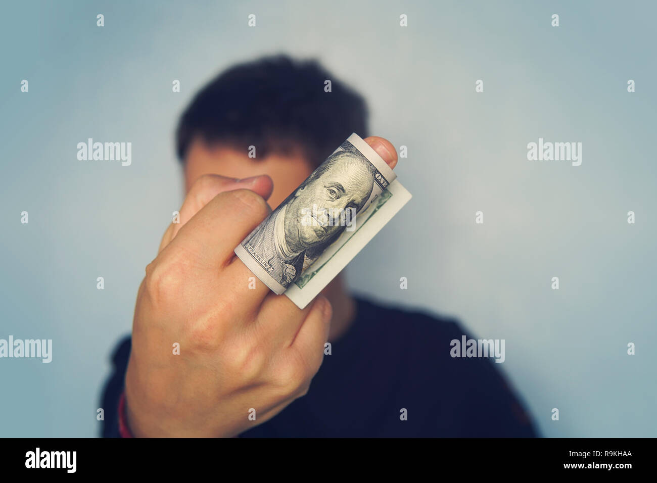 Guy mostra il dito medio su cui sono avvolte 100 dollar banconota di dollari americani. principali mostra il suo atteggiamento verso i poveri. Il concetto di venalità. Foto Stock