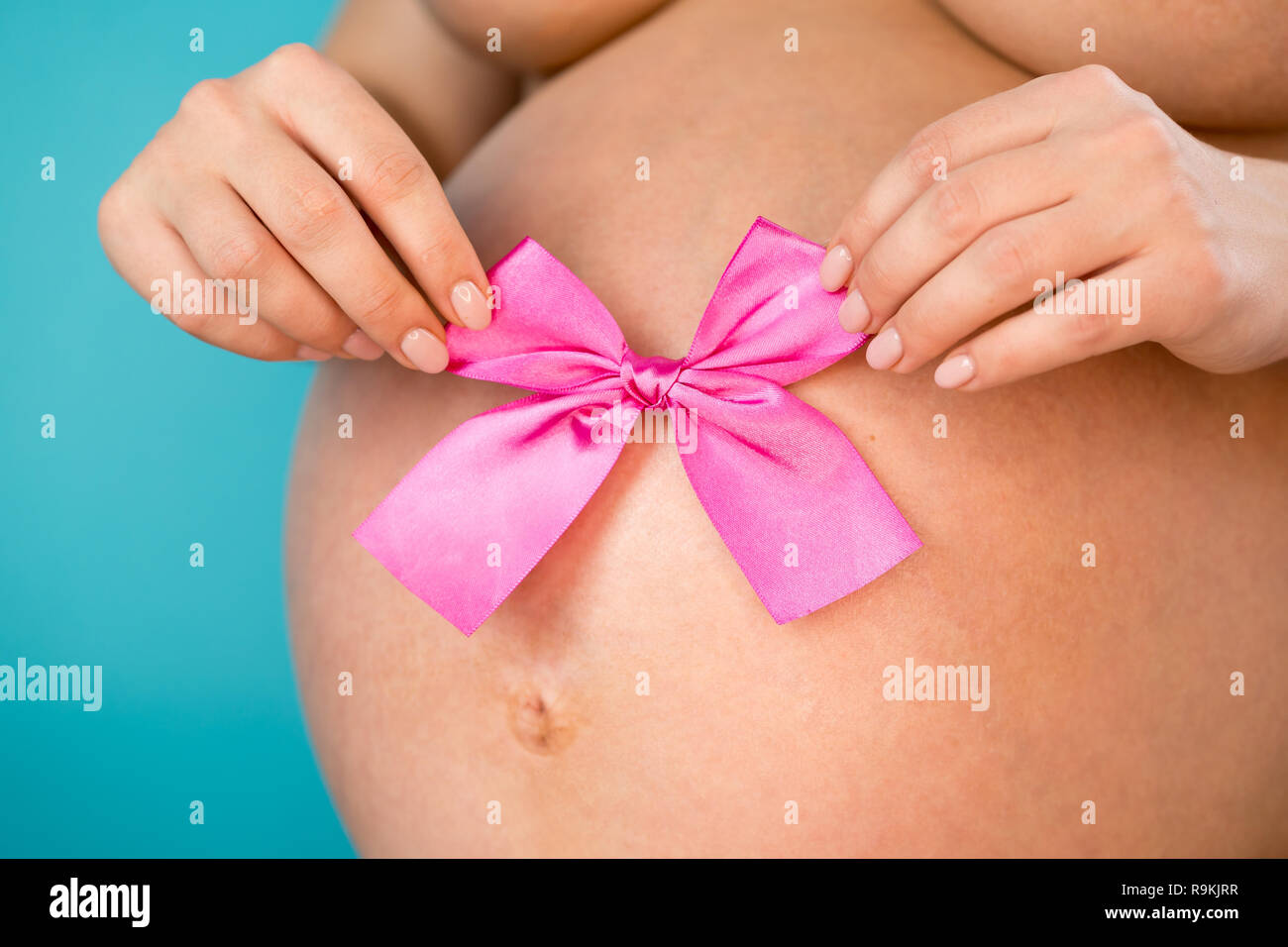 Donna incinta azienda fiocco rosa sulla pancia ventre sfondo. Ragazza  giovane aspetta il bambino. La maternità, la maternità, la gravidanza, il  concetto di amore Foto stock - Alamy