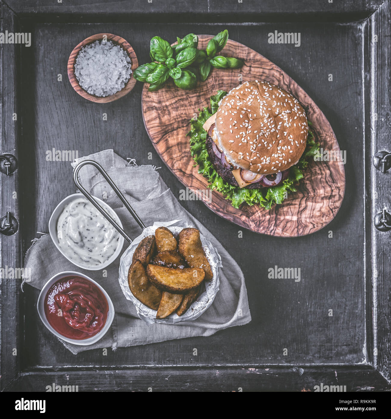 Burger con spicchi di patate su sfondo scuro Foto Stock